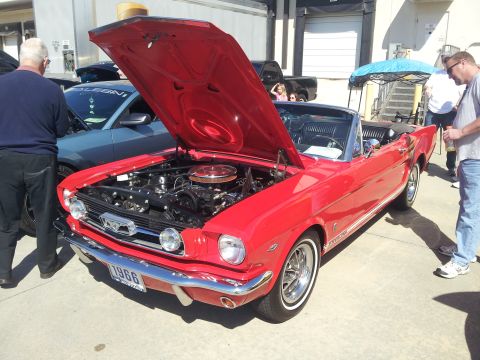 1965 Ford Mustang - A red convertible classic car with its hood open is displayed, revealing the engine and a 1966 license plate.