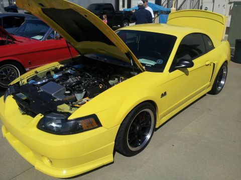 1965 Ford Mustang - This yellow Ford Mustang has its hood and trunk open, revealing the engine bay and rear storage area.