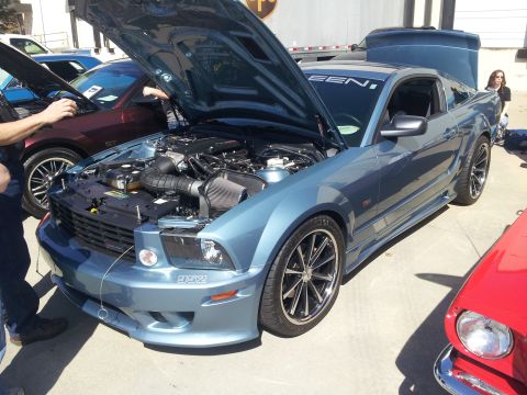 1965 Ford Mustang - A blue Ford Mustang is displayed with its hood open, revealing the engine compartment.