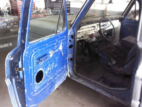 1967 Ford F-100 - Interior view of a blue pickup truck, showing the driver's seat and dashboard with the driver's side door open.