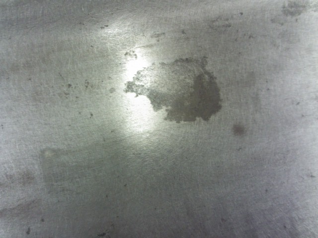 Metal surface with oil stain and Supermotors.net watermark