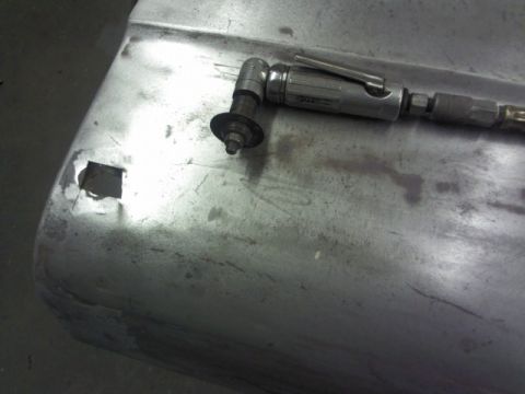 1967 Ford F-100 - A close-up view of a metal panel being worked on with an air tool, showing a square cutout.