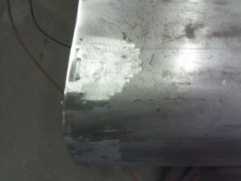1967 Ford F-100 - Close-up of a metal panel undergoing repair, revealing sanding marks and primer.
