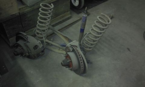 1967 Ford F-100 - Front suspension parts, including coil springs and disc brakes, are shown disassembled on a garage floor.