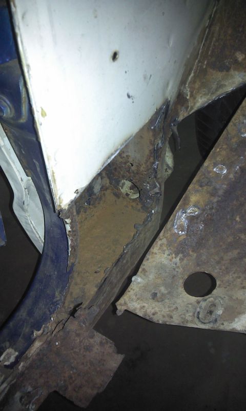 1967 Ford F-100 - Close-up view of heavily rusted metal framing, showing areas of white and blue paint.