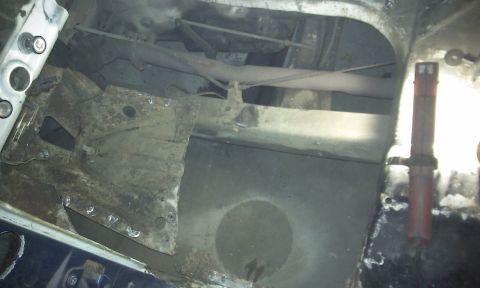 1967 Ford F-100 - Close-up view of a rusted vehicle frame and exhaust system, showing structural components.