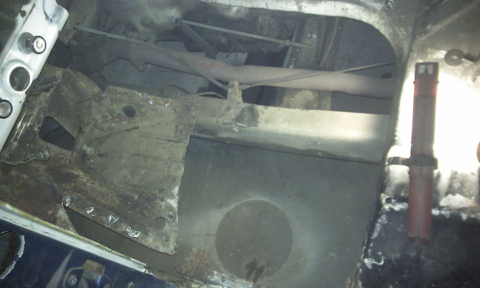 rusted vehicle frame section with exhaust pipe and suspension components visible