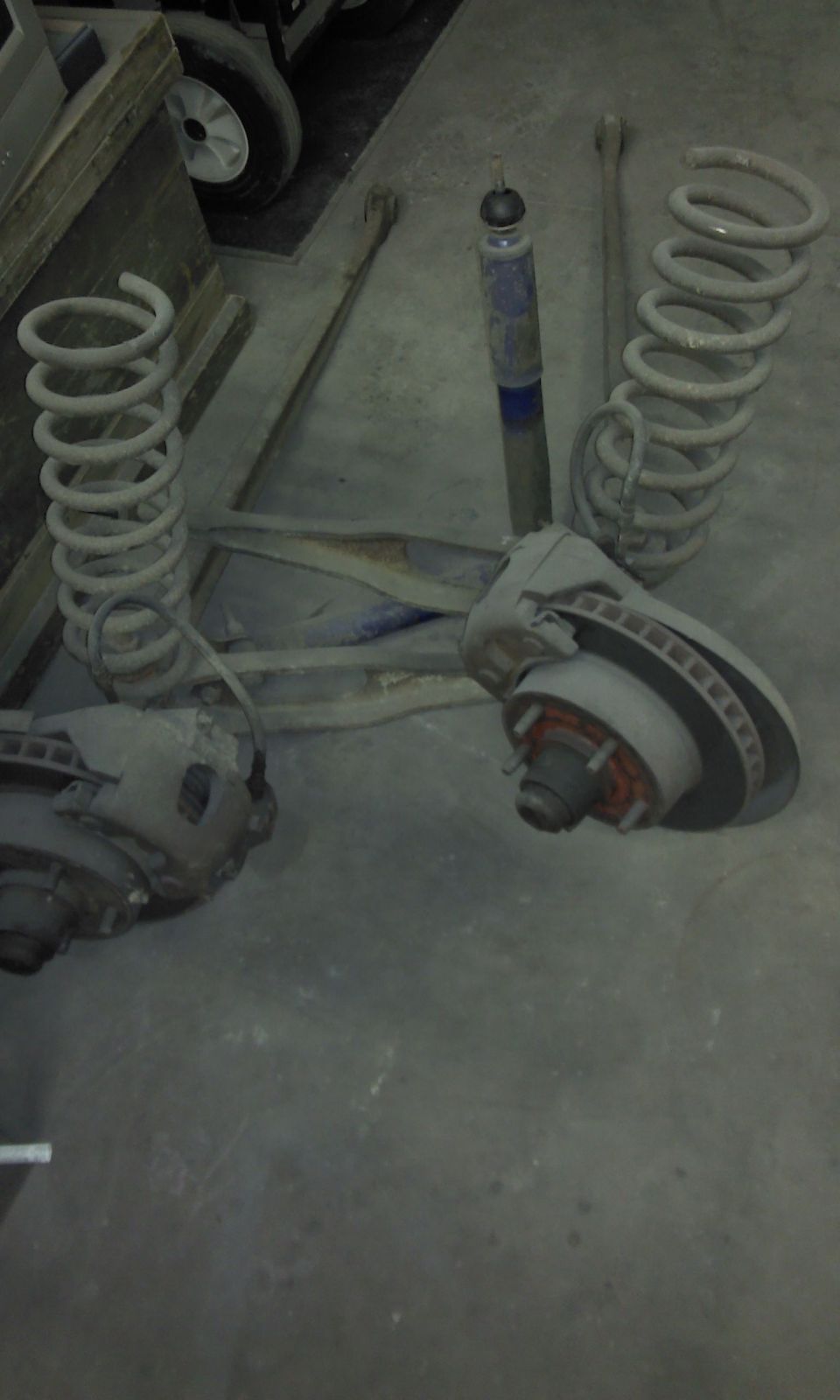 Two coil springs, shock absorber, and brake assemblies on a concrete floor