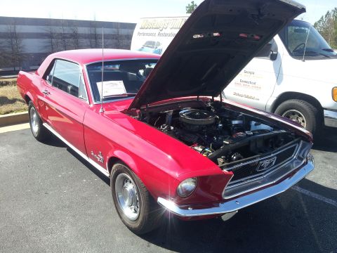1965 Ford Mustang - A red 1967 Ford Mustang coupe is parked with its hood open, revealing the engine bay.