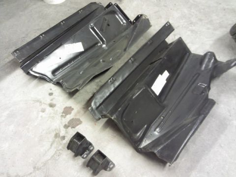 1967 Ford F-100 - Two black metal floor pan sections and two brackets are shown on a concrete surface.