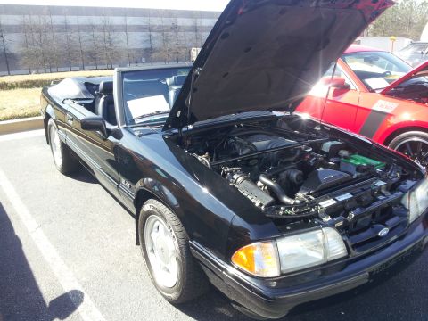 1965 Ford Mustang - This black convertible Mustang, likely a 1987 model, is displayed with its hood open, revealing the engine compartment.