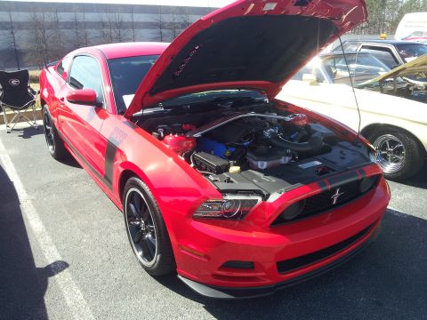 1965 Ford Mustang - Red Ford Mustang Boss 302 on display with hood open, parked next to another vehicle.