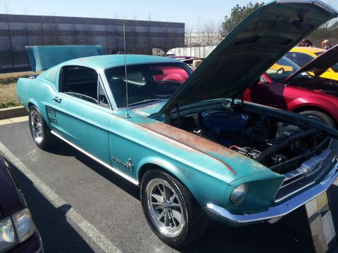 1965 Ford Mustang - A turquoise 1967 Ford Mustang is parked with its hood open, revealing the engine bay.