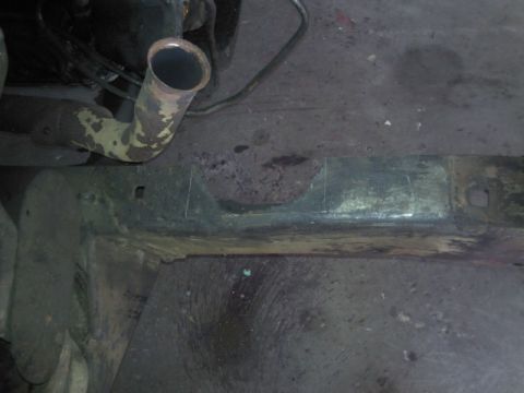 1967 Ford F-100 - The underside of a vehicle shows a section of the frame and a bent exhaust pipe.
