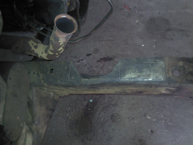 Close-up of a rusty vehicle frame with an exhaust pipe visible