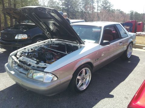 1965 Ford Mustang - A two-door coupe with its hood open, revealing the engine bay, parked outdoors.