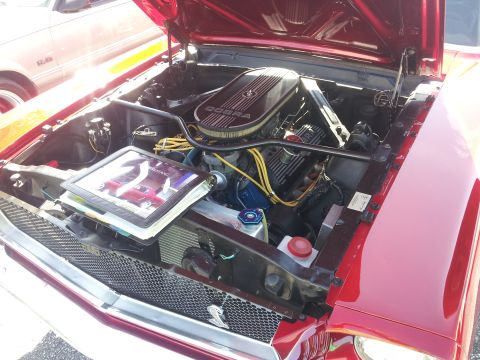 1965 Ford Mustang - The engine bay of a 1965 Ford Mustang is displayed, a Cobra air cleaner and a book open to an image of the car.