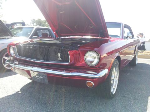 1965 Ford Mustang - Front view of a red 1965 Ford Mustang coupe with its hood open, parked outdoors.