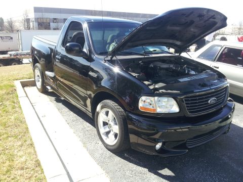1965 Ford Mustang - This black 1999 Ford F-150 Lightning pickup truck is shown with its hood open, revealing the engine bay.