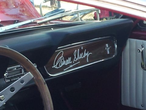 1965 Ford Mustang - The dashboard features a Carroll Shelby signature plate and a Mustang emblem, indicating a special edition.
