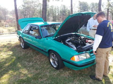 1965 Ford Mustang - Teal Ford Mustang with hood and trunk open, engine bay visible, two men observing.