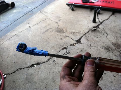 1996 Ford Bronco - A tool modified with tape to hold a nut is shown against a cracked concrete surface.