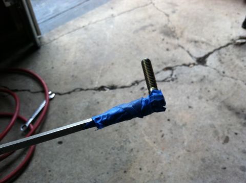 1996 Ford Bronco - A bolt with blue tape wrapped around its shaft is shown, likely for a spring hanger replacement.