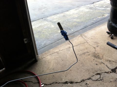 1996 Ford Bronco - A metal tube, possibly a brake line or fuel line, is shown with blue tape on its threaded end.