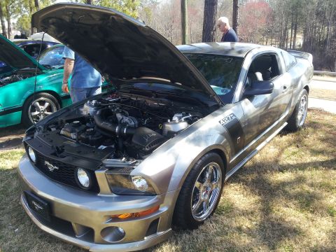 1965 Ford Mustang - Silver Ford Mustang 427R on display with its hood open, revealing the engine and custom wheels.