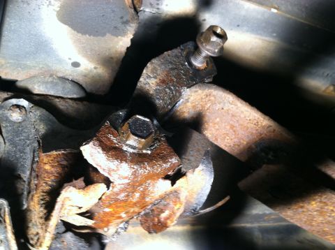 1996 Ford Bronco - Close-up of a heavily rusted suspension component, likely a spring hanger, showing significant wear and tear.