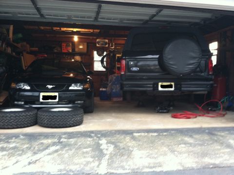1996 Ford Bronco - A black Ford Bronco is parked in a garage next to a black Ford Mustang.