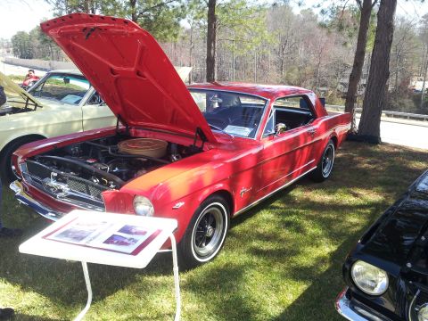 1965 Ford Mustang - 1965 Ford Mustang coupe on display with hood open, revealing the engine bay.