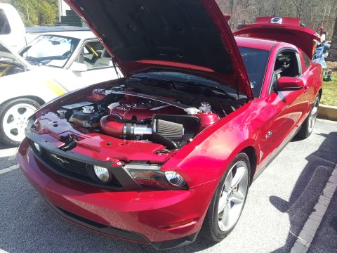 1965 Ford Mustang - A red Ford Mustang is parked with its hood and trunk open, revealing the engine bay.