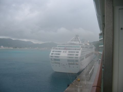 1992 Ford Bronco - A large cruise ship is docked at a port on a cloudy day, with land and mountains visible in the distance.