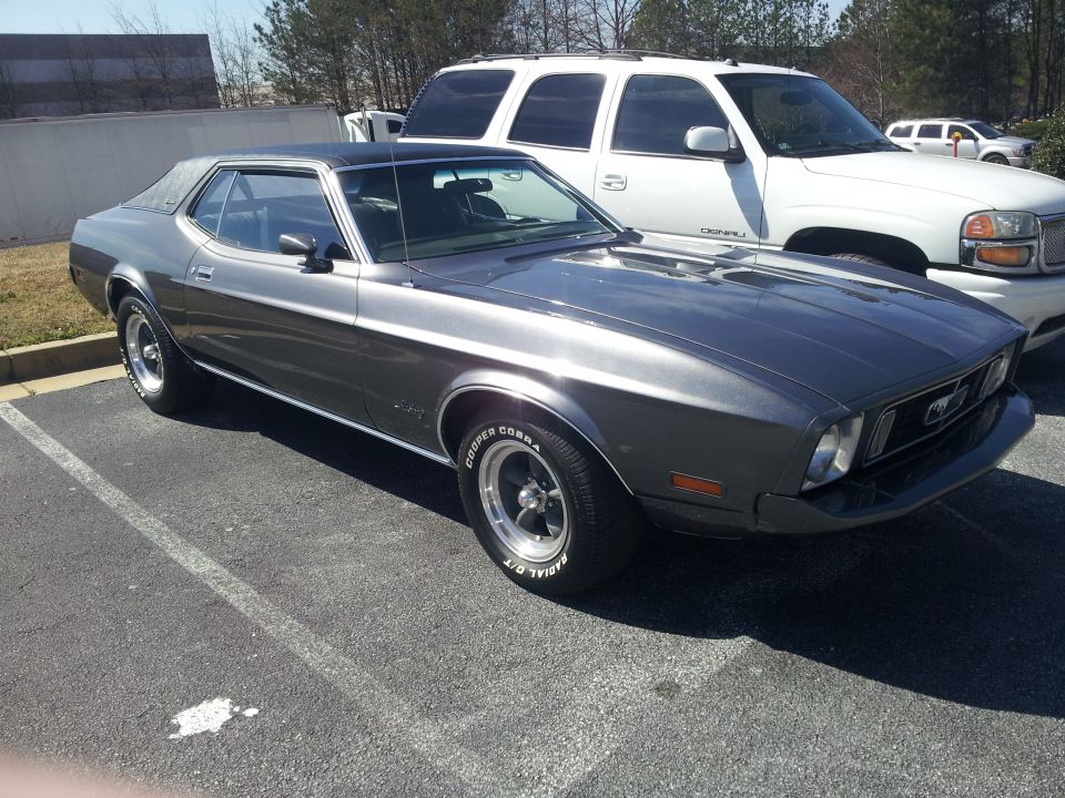 Gray 1971 Ford Mustang coupe parked next to a white SUV