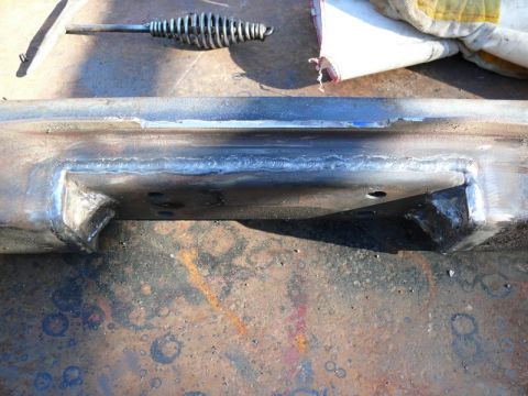 1976 Chevrolet Corvette - A metal frame part shows fresh welds, with a tool and a gloved hand in the background.