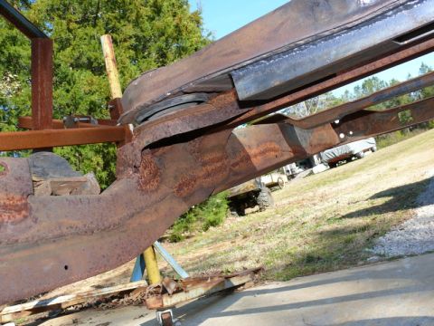 1976 Chevrolet Corvette - A heavily rusted vehicle frame is supported by stands outdoors, with other vehicles visible in the background.