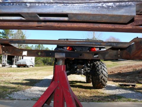 1976 Chevrolet Corvette - The rear of an ATV is visible between rusty metal frame pieces, supported by red jack stands.