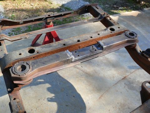 1976 Chevrolet Corvette - Vehicle frame with visible rust and recent welds, supported by red jack stands outdoors.
