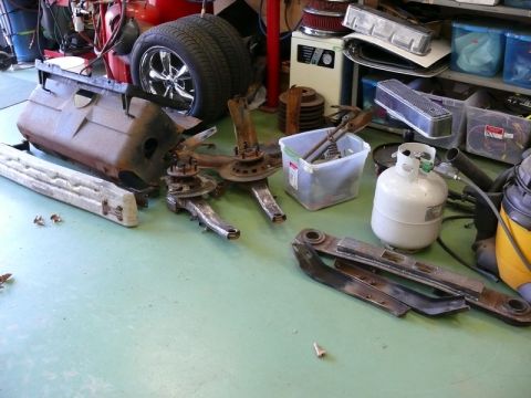 1976 Chevrolet Corvette - Various disassembled car parts are laid out on a light green floor, suggesting a repair or restoration project.