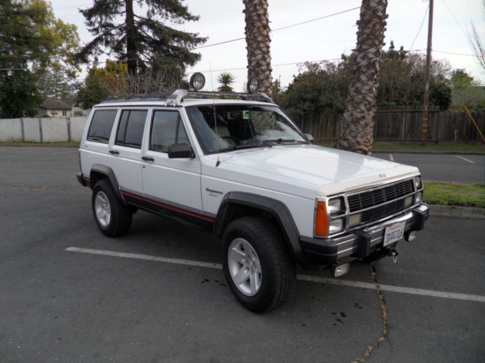 White 1994 Jeep Cherokee with roof rack and off-road lights