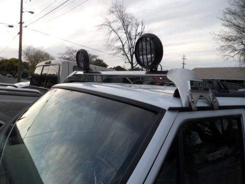 1994 Jeep Cherokee - Off-road accessories including lights and a snorkel are mounted on the roof rack of a white SUV.