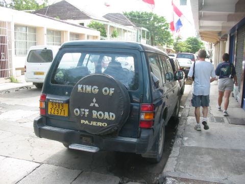 1992 Ford Bronco - A Mitsubishi Pajero is parked on the side of a street, with a spare tire cover that reads 'King of Off Road'.