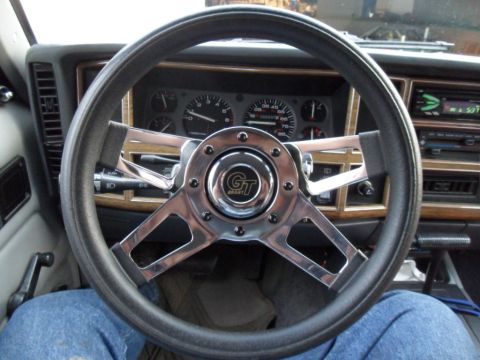 1994 Jeep Cherokee - The interior of a 1994 Jeep Cherokee features an aftermarket Grant steering wheel and wood-grain trim on the dashboard.