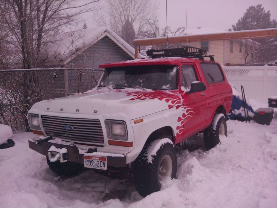 Red and white SUV parked outside in snowy weather. Roof rack visible on top