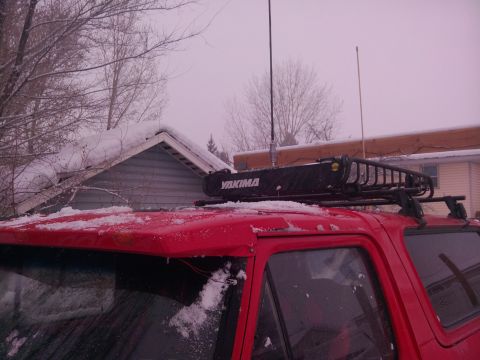 1979 Ford Bronco - A close-up view of a roof rack mounted on a red vehicle, with a blurred background.