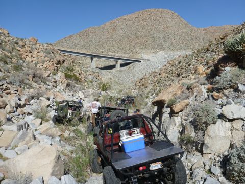 1997 Ford Ranger - Multiple off-road vehicles traverse a desert landscape with a bridge overhead.