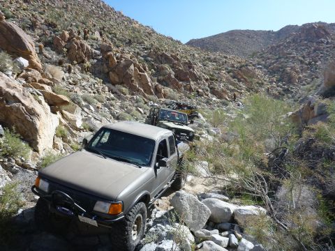 1997 Ford Ranger - Off-road vehicles, including a 1997 Ford Ranger, traverse a challenging rocky path in a desert landscape.