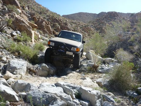 1997 Ford Ranger - A modified 1997 Ford Ranger navigates a rocky off-road path in a desert landscape.