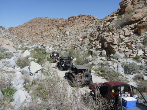 1997 Ford Ranger - Multiple off-road vehicles navigate a desert path under a clear blue sky.